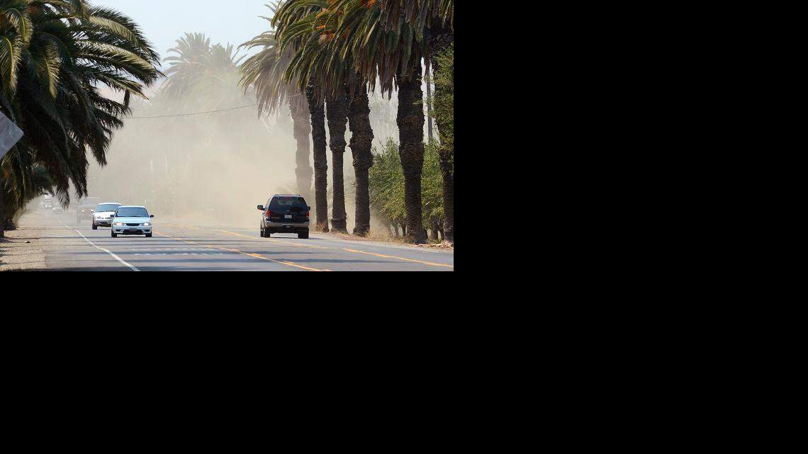 Motorists navigate through clouds of dirt stirred up from almond harvesting along East Las Palmas Avenue outside of Patterson in 2013.