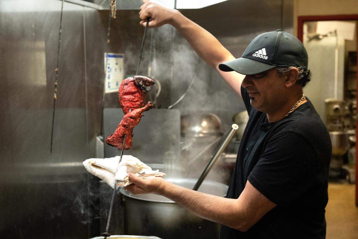 Owner Deepak Dogra pulls out tandoori chicken from the oven at Tandoori Masala in Modesto, Calif., Thursday, Dec. 8, 2022.
