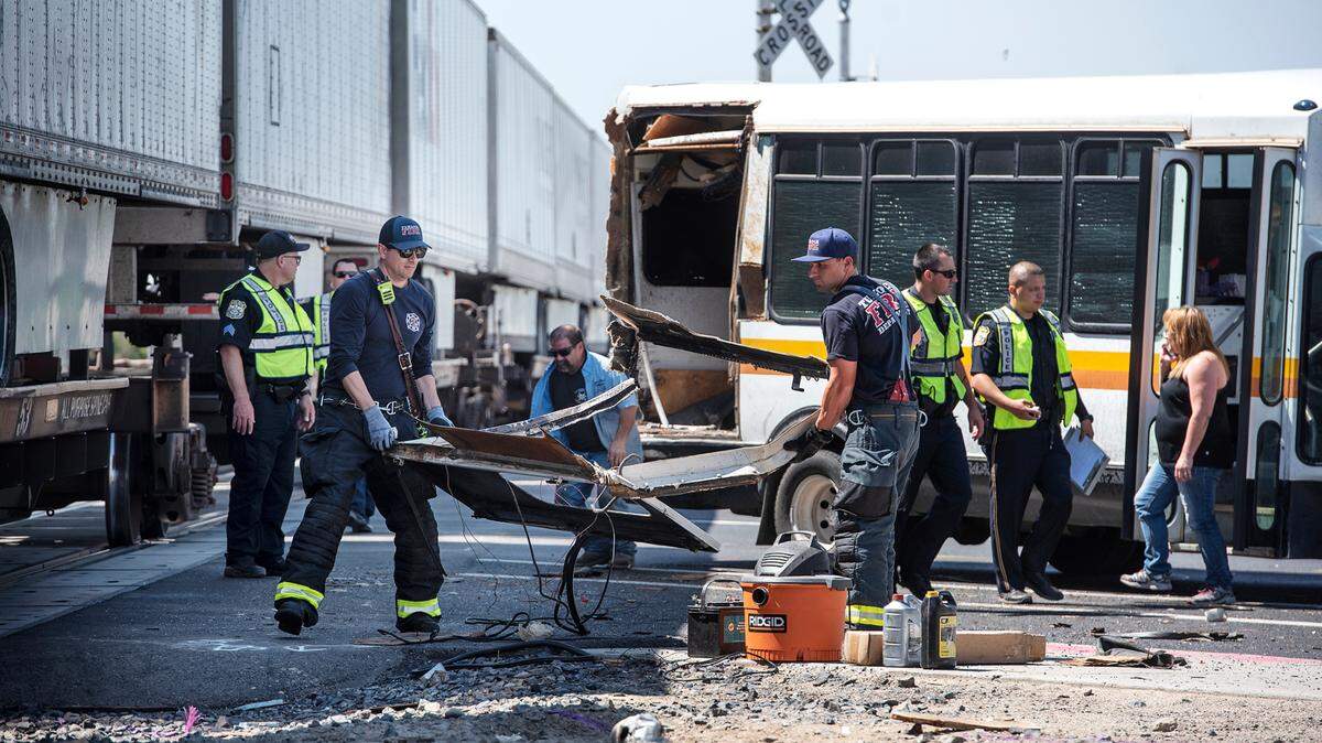 Turlock Firefighters clear debris after a small bus was struck by a freight train on Monte Vista Avenue in Turlock, Calif., Friday, May 10, 2019.