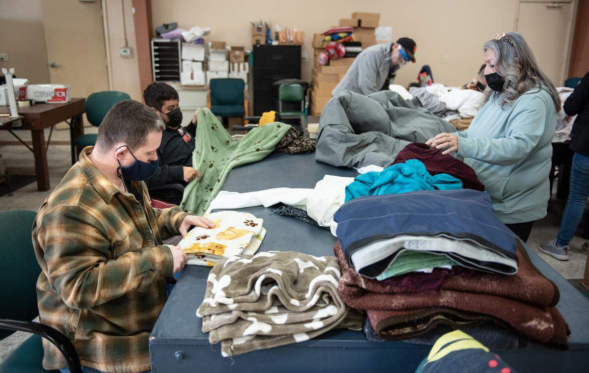 Terry McConnell, left, Jose Garcia and job coach Monica Avila, right, fold blankets for a local hospice at Howard Prep in Ceres, Calif., Wednesday, Feb. 21, 2023.