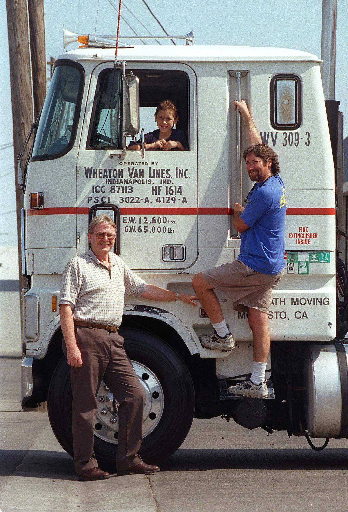 This 1999 photo shows three generations: owner Terry McGrath, 59, son Mike McGrath, 36, hanging off footstep, and Nicholas McGrath, age 8. McGrath celebrated 50 years of business that year.