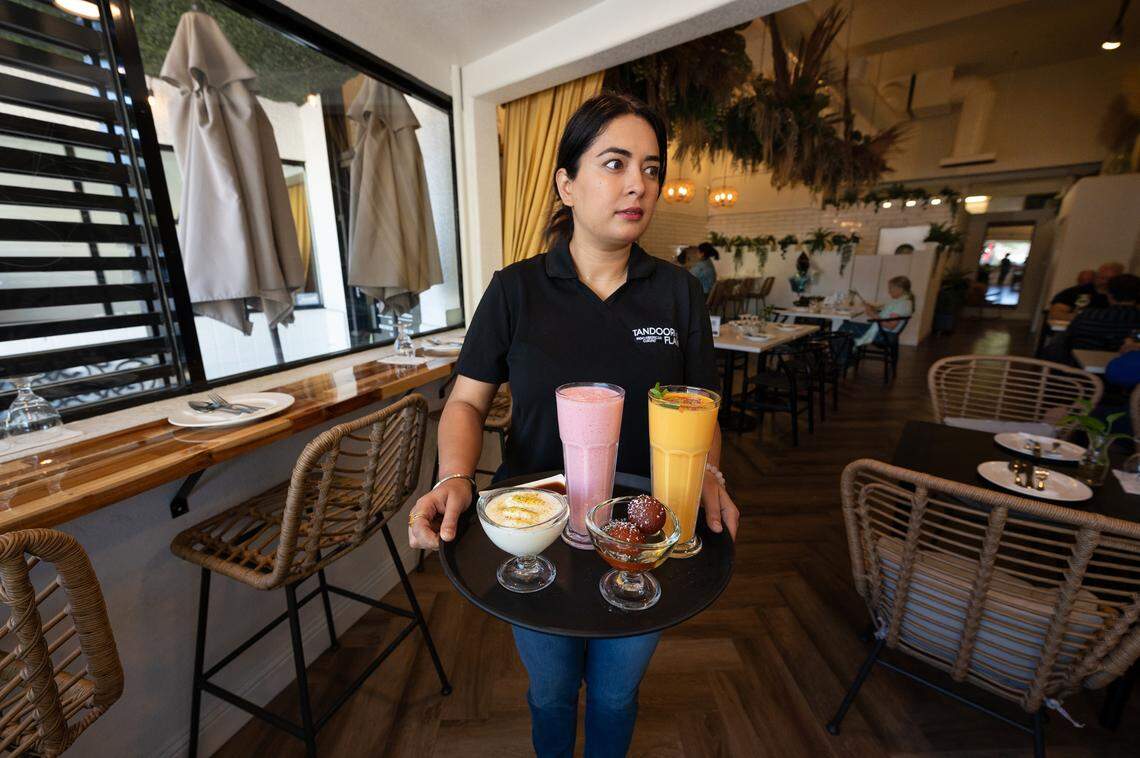 Co-owner Simran Dhanju delivers desserts at Tandoori Flame restaurant on 10th Street in Modesto, Calif., Wednesday, Sept. 27, 2023. The desserts Gulab Jamun (dumplings made of thickened milk in syrup) and Rasmalai (spongy ras in malai cream) with mango and strawberry lassi (yogurt and fruit).
