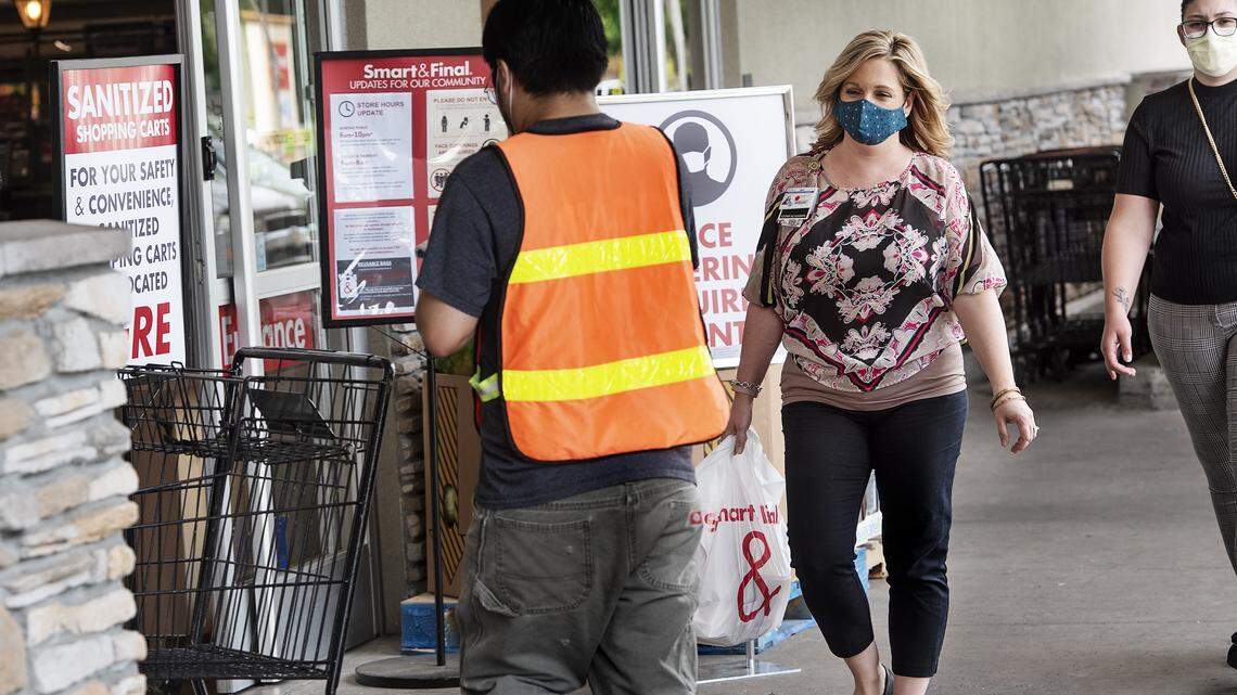 Cassandra Peralta, middle, and Corina Summers, right, leave the Smart & Final store in Modesto, Calif., on Wednesday, April 29, 2020. Shoppers and employees are now required to wear a face coverings to shop at the store.