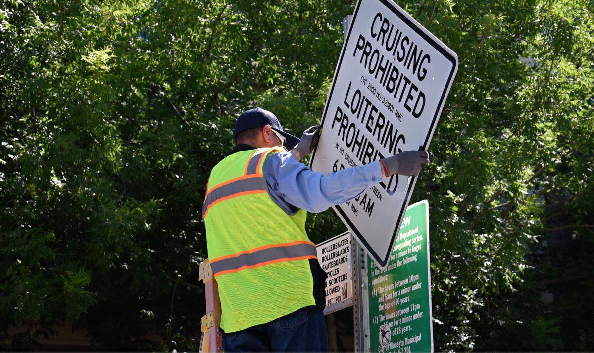 Modesto city employee William George removes the last “no cruising” sign from downtown in Modesto, Calif., Saturday, July 15, 2023. The City Council voted unanimously Tuesday to repeal the 1990 cruising ban, ending it effective immediately.