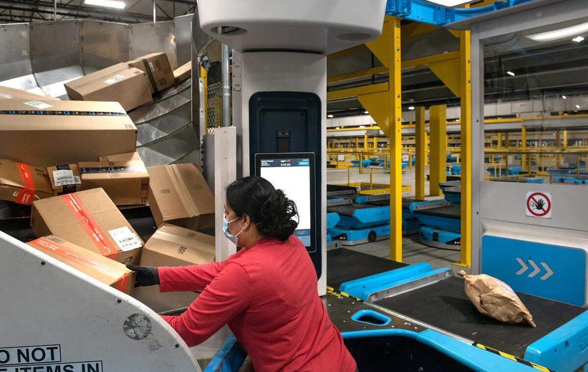 Amazon employee Ramandeep Sandhawalia loads packages onto sorting robots at the Amazon robotic sort center in Tracy, Calif., Thursday, Nov. 10, 2022.