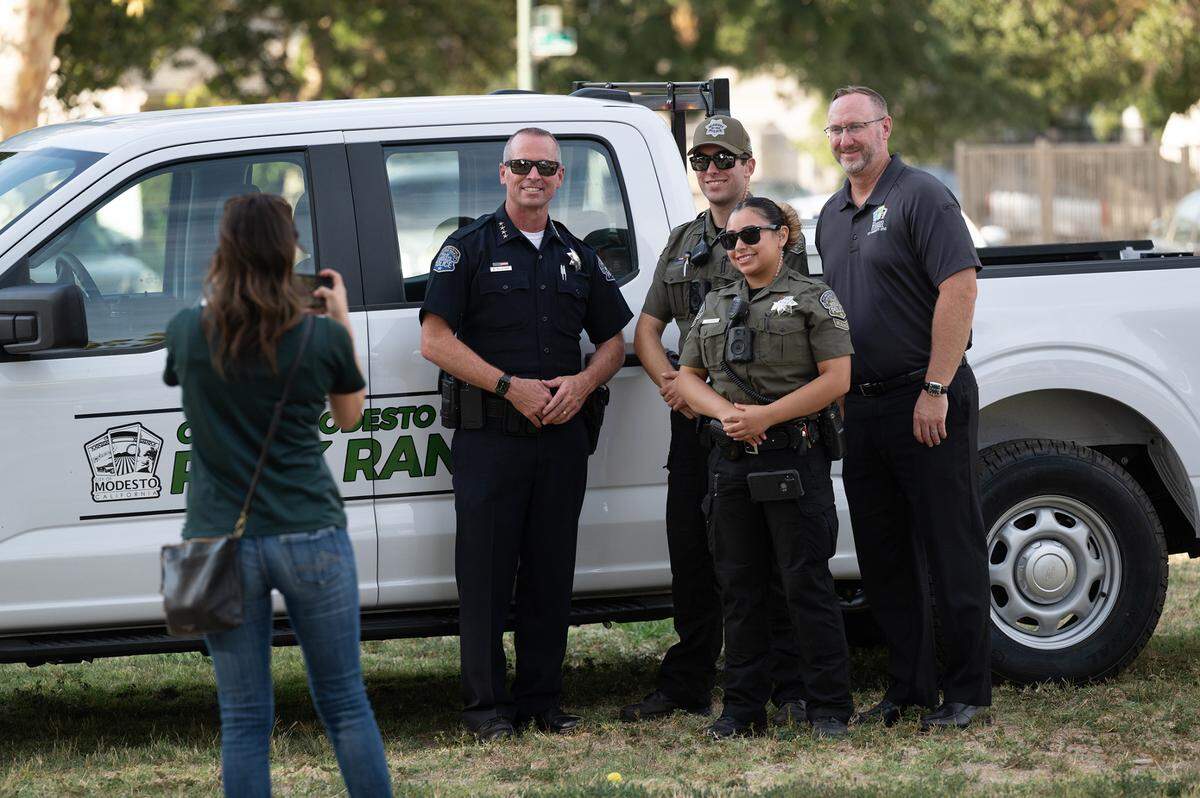 Park rangers Justin Rocha and Ivonne Salamanca take a picture with Modesto Police Chief Brandon Gillespie, left, and Joe Lopez, city manager, right, during National Night Out at Cesar Chavez Park in Modesto in August.