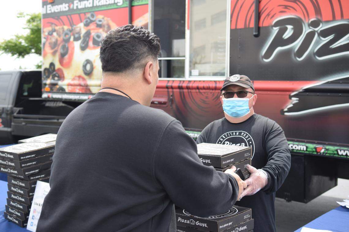 Pizza Guys franchise owner David Gambrel gives a pizza to a Kaiser healthcare worker on Wednesday, April 8, 2020 in Modesto, Calif. The company gave over 1,400 pizzas to healthcare workers.