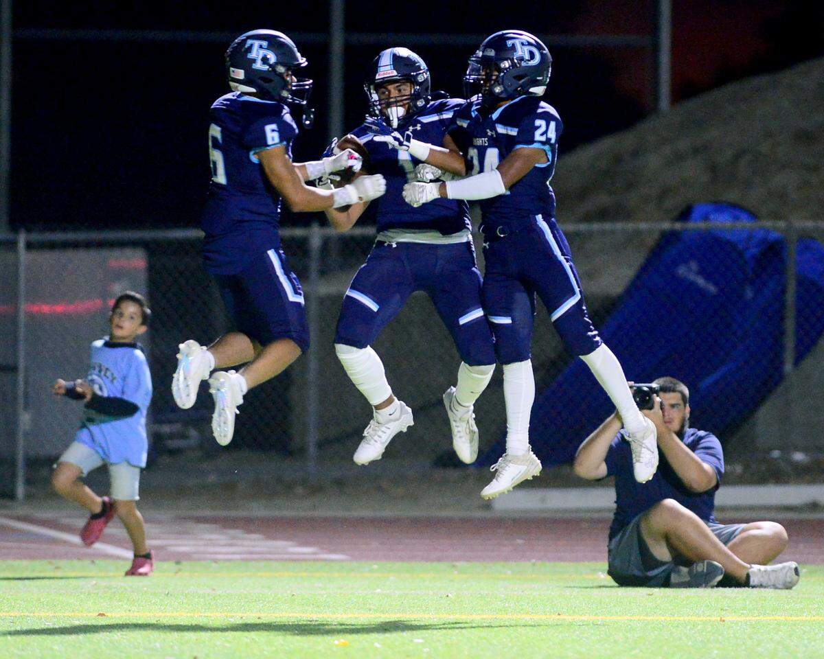 Downey receiver Nathan Dip (center) celebrates with teammates Melo Thurman (6) and Marcus Cruz (24) during a game between Downey High School and Merced High School at Downey High School in Modesto California on September 1, 2023.
