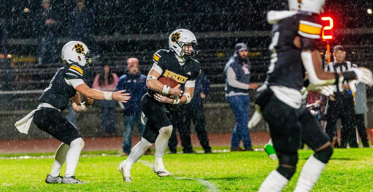 Eli Wilbanks, 21, gets a handoff from Robert McDaniel, 8, of Hughson High during the Sac-Joaquin Section Division V Semifinals against Union Mine on at Hughson High School on Friday, Nov. 22, 2024.