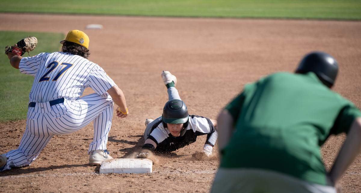 Pitman’s Cole Kelley dives back to first on a pick-off play during the California Athletic League game with Turlock at Turlock High School in Turlock, Monday, April 14, 2025.