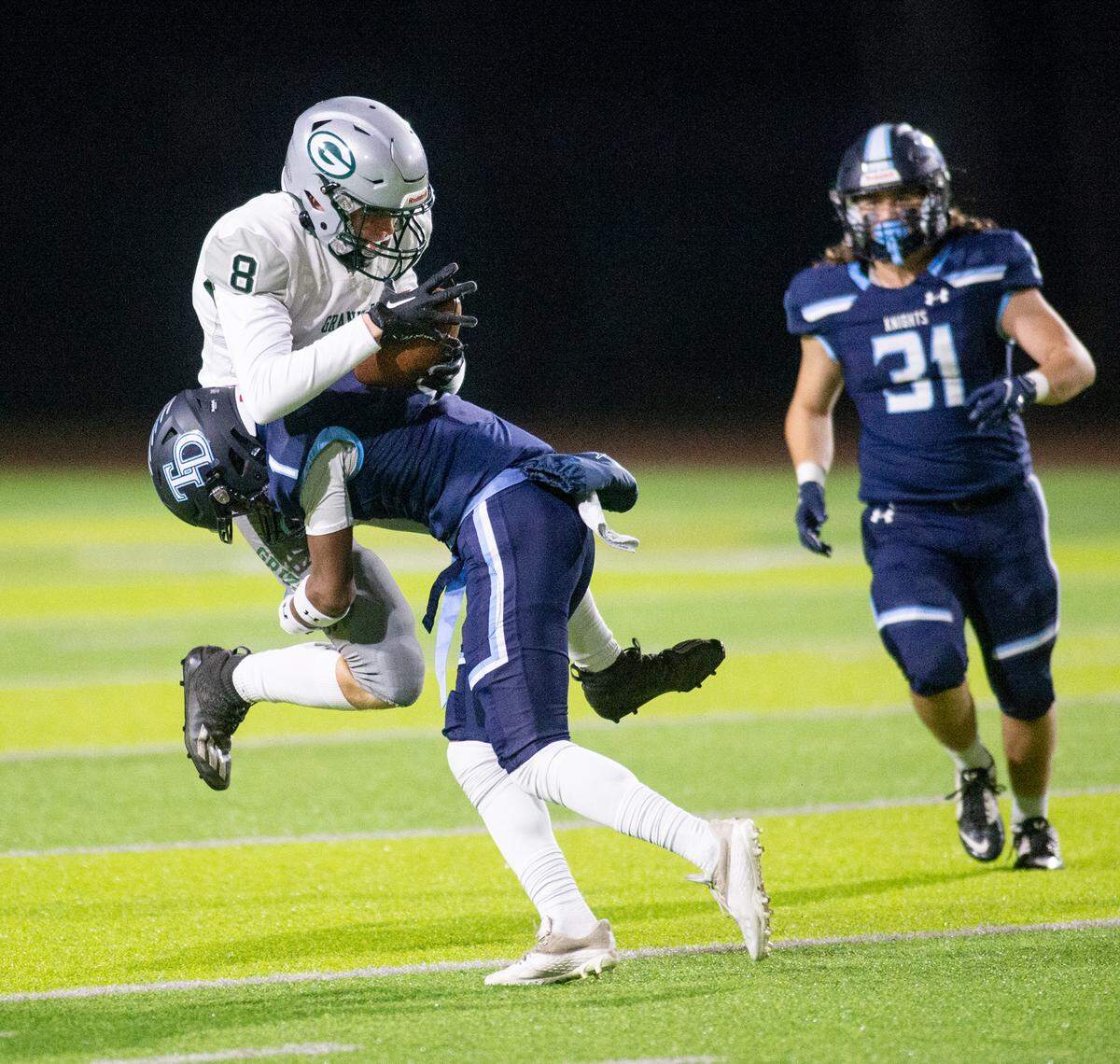 Granite Bay’s Eddie Thomas (8) holds on to the ball after a hit from Downey’s Jeremiah Stine during the CIF Sac-Joaquin Section Division II playoff game at Downey High School in Modesto, Calif., Friday, Nov.11, 2022. Granite Bay won the game 42-24.