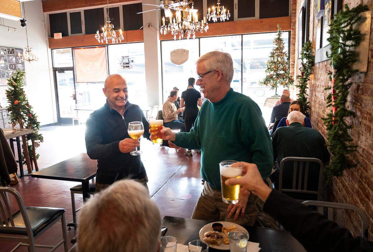 Barkin’ Dog Grill owner Hanibal Yadegar, left, shares a toast with longtime customers Mark Looker, right, Kevin Leppla and Darin Willliams (not pictured) in Modesto, Calif., on Thursday, Dec. 16, 2021.