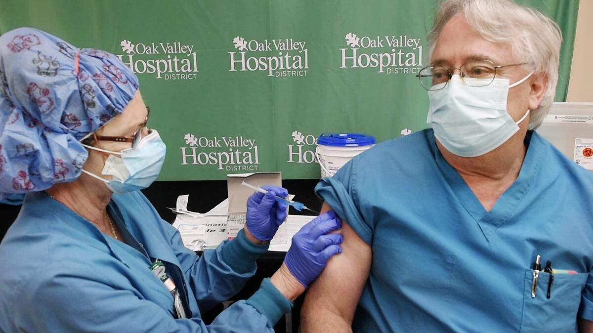 Nurse Regina Singh, left, gives nursing manager Denis Garrison the COVID-19 vaccine at Oak Valley Hospital in Oakdale, Calif., Friday, Dec. 18, 2020.