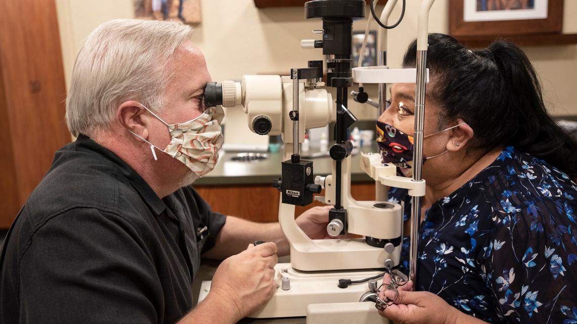 Optometrist Eric Miedema checks the contact lens of client Lydia Castaneda in Modesto, Calif., on Friday, June 26, 2020.