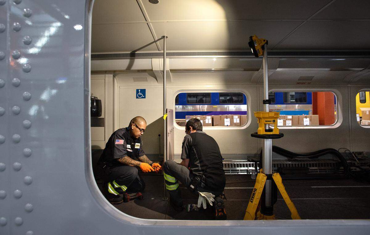 Technicians Sebastian Eth, left, and Nick Fortune, right, demonstrate some of the work that is done at the Altamont Corridor Express maintenance facility during an open house to announce the creation of the Rail Academy of Central California in Stockton, Calif., on Wednesday, May 25, 2022. The program will launch in August, with classroom training at a community college and hands-on work at the ACE maintenance facility.