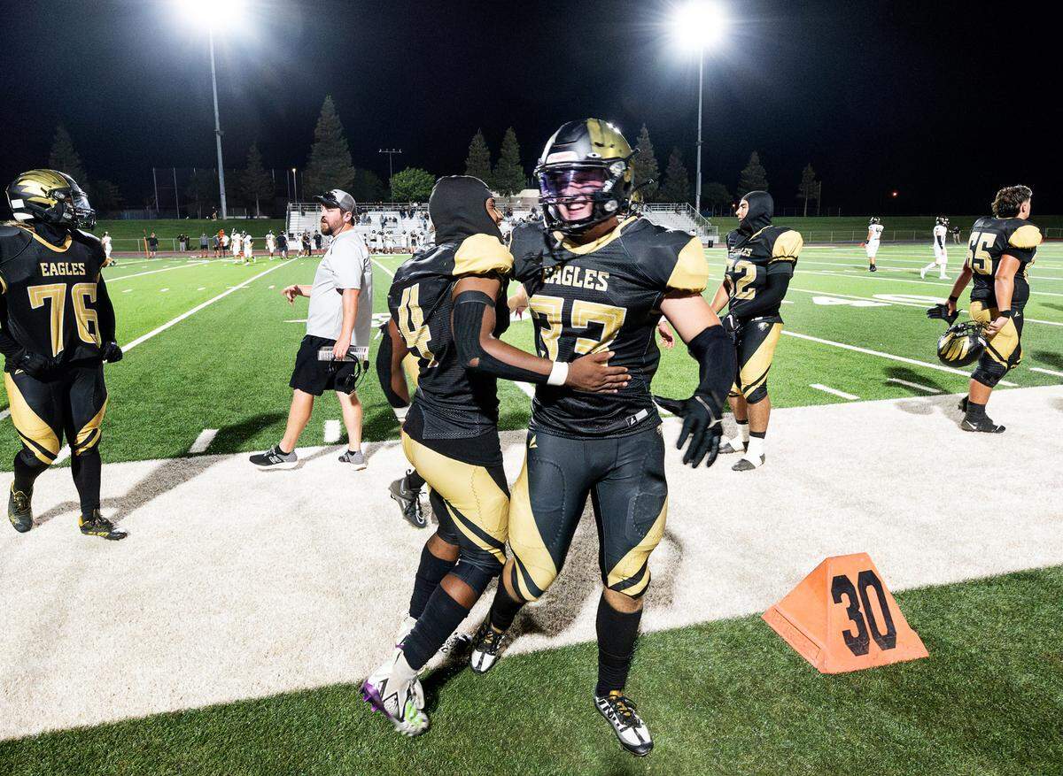 Enochs’ Aiden Muhammad, left, greets Kaedon Kopp on the sideline after Kopp scored on a touchdown run during the non-league game with Buhach Colony at Gregori High School in Salida, Calif., Friday, Sept. 1, 2023. The Eagles won the game 54-8.