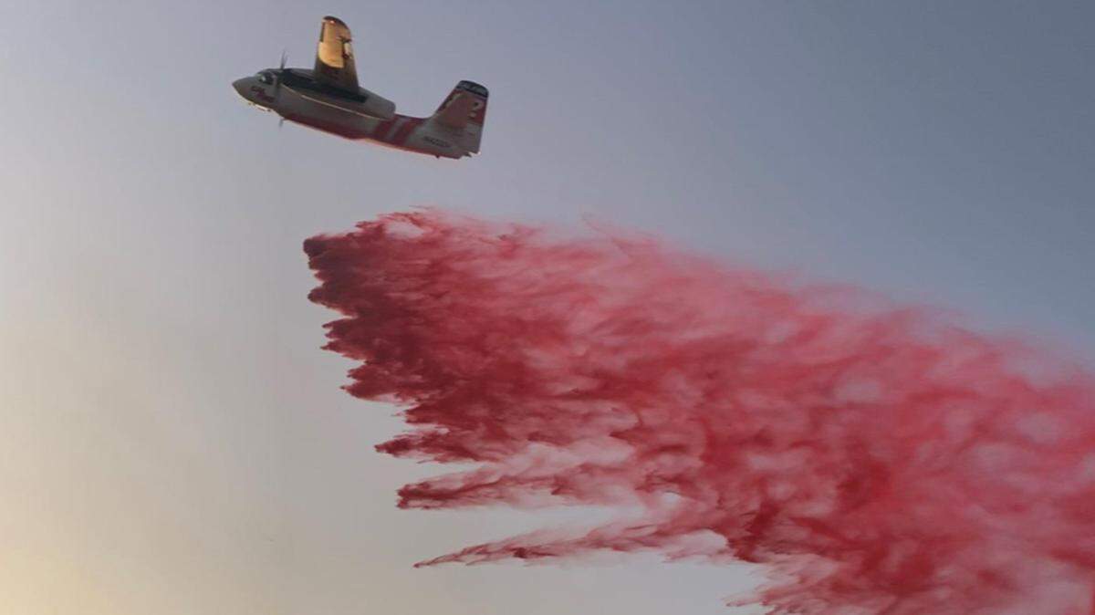 A plane drops fire retardant on a grass fire on Monday, Oct. 7, 2019, northeast of Modesto Reservoir, California. The fire was started by a small plane crash.