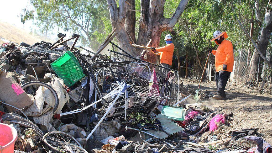 Workers for Caltrans clean up the remains of a homeless encampment in Turlock, Calif. on Wednesday, May, 12, 2021.