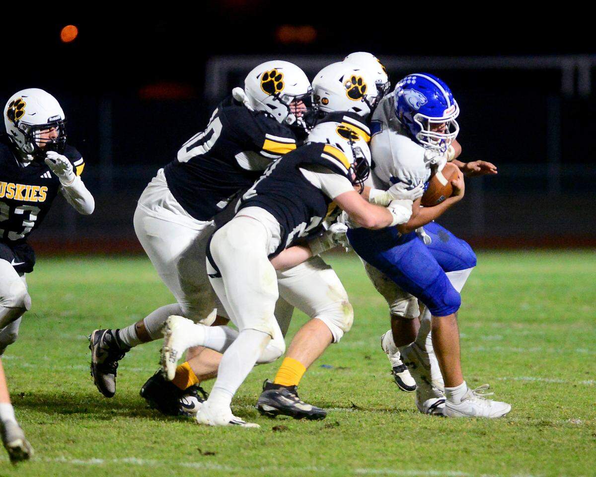 Multiple Hughson High defenders sack El Dorado quarterback Jason Wilson (4) during a 2024 CIF Sac-Joaquin Section Division V Playoff game between Hughson High School and El Dorado High School at Hughson High School in Hughson California on November 15, 2024. Hughson won the game 28-6.