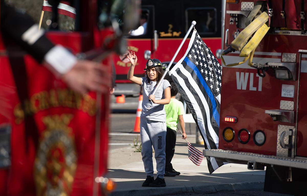 Justice Baca, 10, waves to firefighter during the final processional for fallen Stockton Fire Capt. Vidal “Max” Fortuna in Stockton, Calif., on Tuesday, Feb. 8, 2022. Thousands of firefighters were on hand in Stockton to remember Fortuna, coming from as far away as Minnesota.