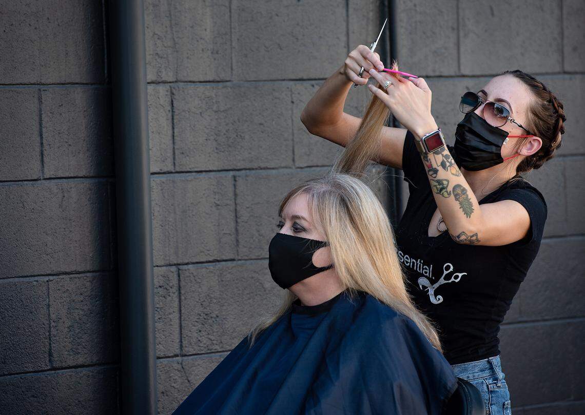 Volume Salon stylist Kayla Royal cuts the hair of Beth Garcia outdoor haircut during a fundraiser at Bottles and Blades in Modesto, Calif., on Thursday, August 6, 2020.