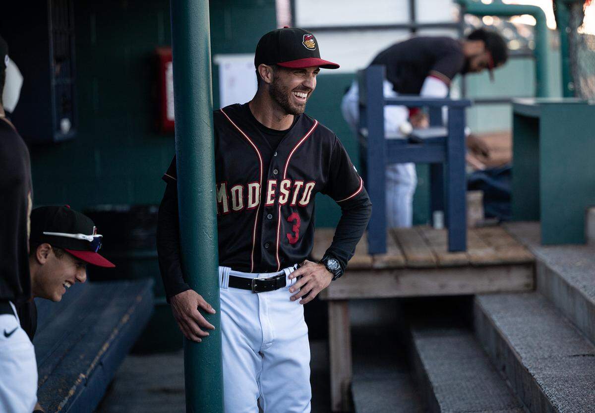 Modesto Nuts manager Austin Knight, right, shares a light moment with players in the dugout before the California League game with the Stockton Ports at John Thurman Field in Modesto, Calif., on Wednesday, July 6, 2022.