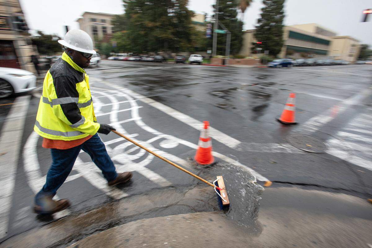 A city utilities worker helps flush out a storm drain on I Street in Modesto, Calif., Tuesday, Nov. 1, 2022.