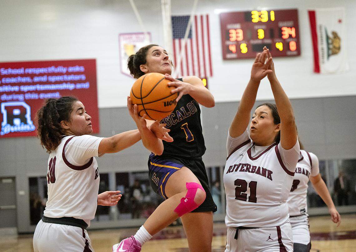 Escalon’s Sammy Lang attacks the basket as Riverbank’s Chancis Gamez, left, and Haley Barker, right defend during the Trans Valley League game at Riverbank High School in Riverbank, Calif., Thursday, Jan. 4, 2024. Escalon won the game 52-51.