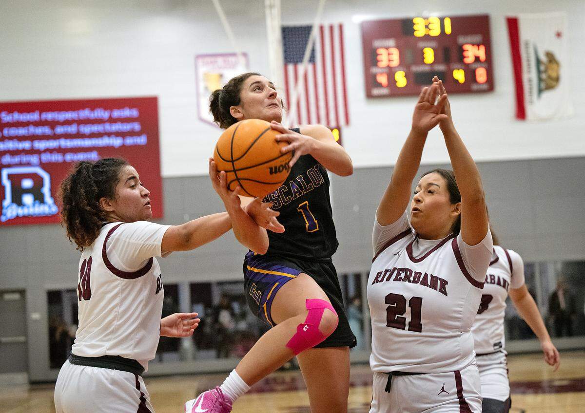 Escalon’s Sammy Lang attacks the basket as Riverbank ’s Chancis Gamez, left, and Haley Barker, right defend during the Trans Valley League game at Riverbank High School in Riverbank, Calif.,Thursday, Jan. 4, 2024. Escalon won the game 52-51.