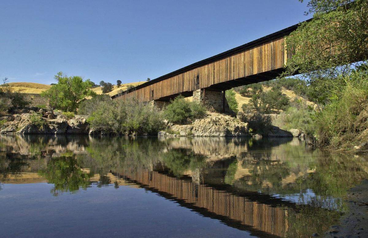 The covered bridge over the Stanislaus River at Knights Ferry was built in 1854 and restored in 1989. The longest covered bridge in the western United States-- 330 feet-- the span has been part of the US Army Corps of Engineers park at Knights Ferry since 1979 and closed to vehicle traffic since 1981. Photographed on Tuesday 8/17/04.