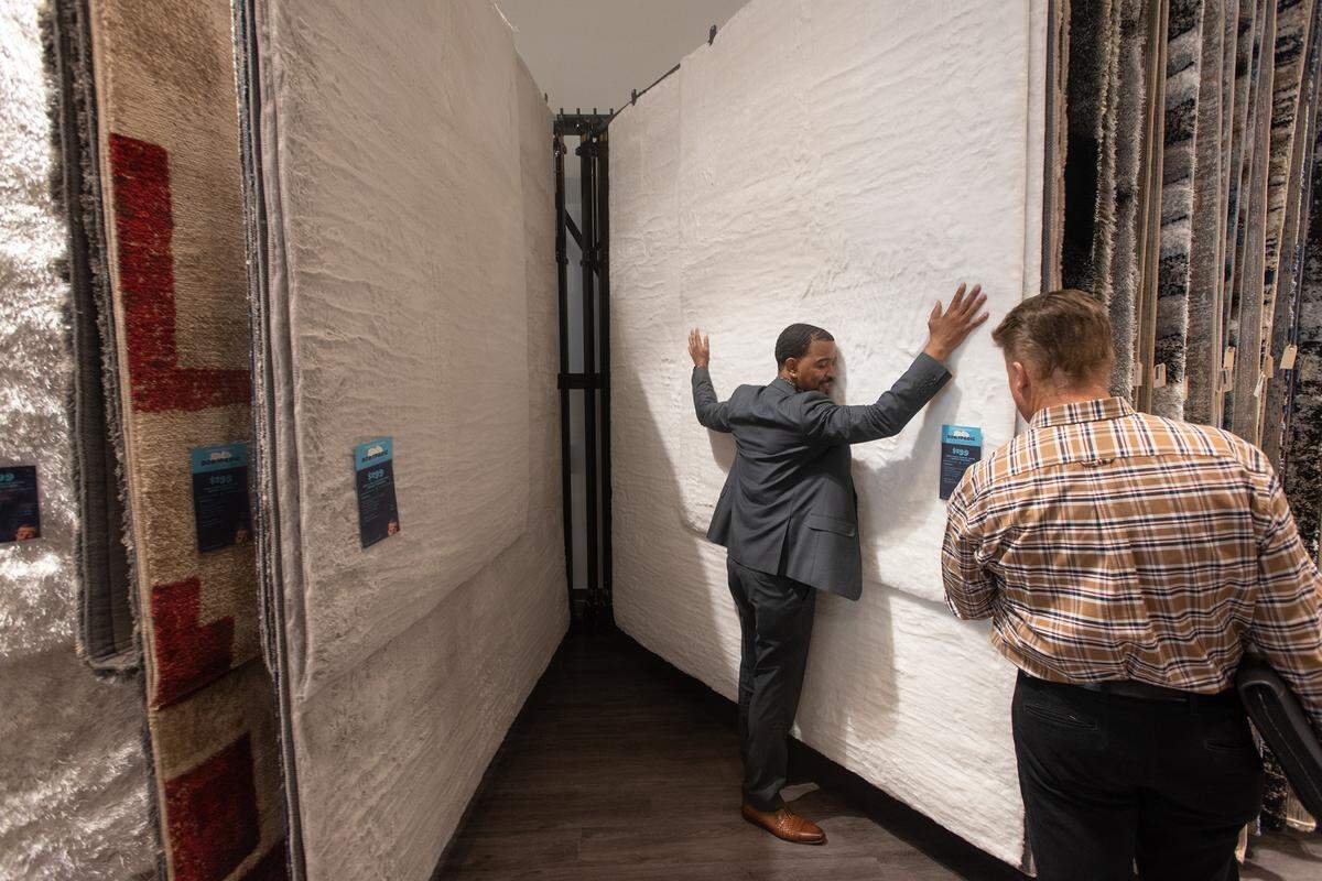 Assistant manager Brenden Reilly shows off carpets at Bob’s Furniture in Modesto Calif., on Friday, May 27, 2022.