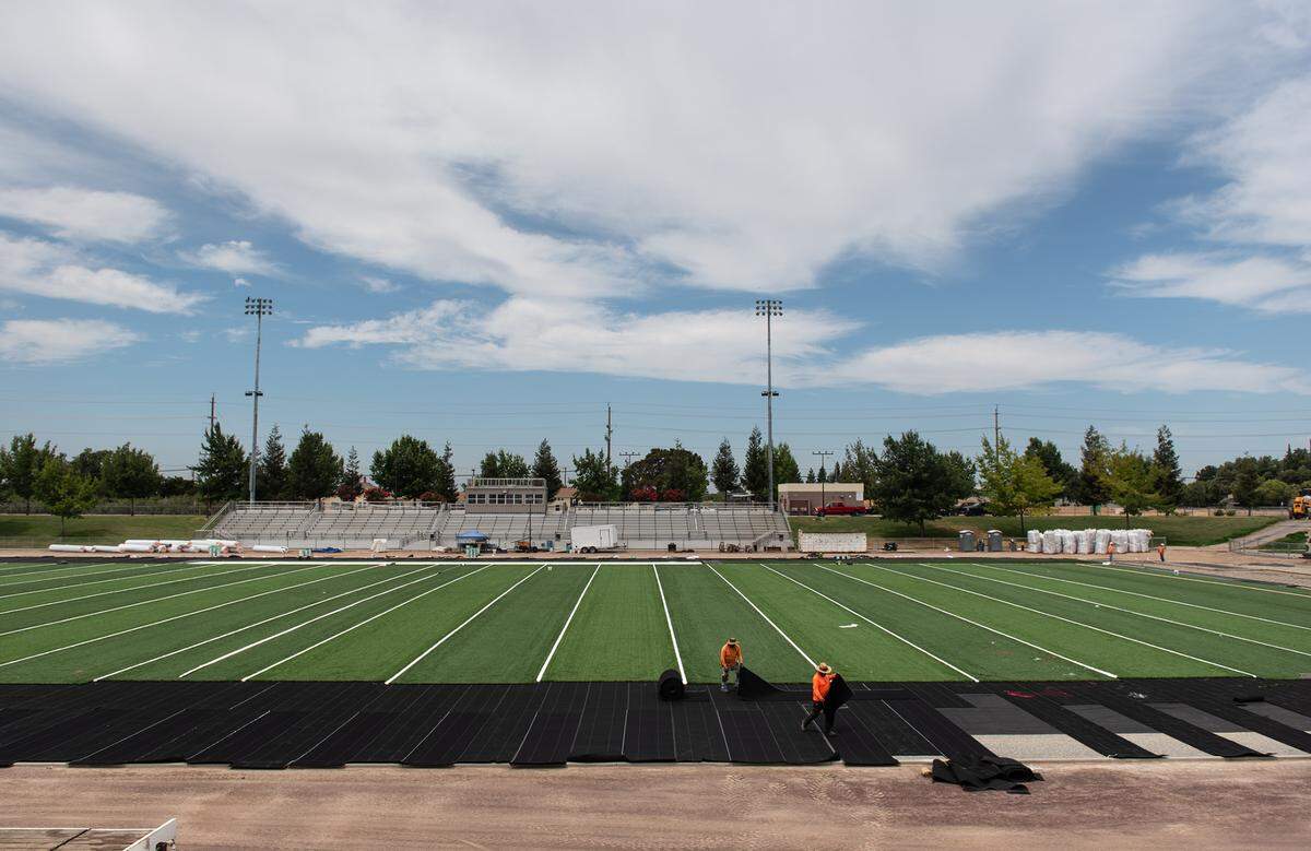 Sergio Casillas and Balthazar Alas from Valley Precision Grading work on installing new artificial turf at Gregori High School in Salida, Calif., on Friday, August 5, 2022.