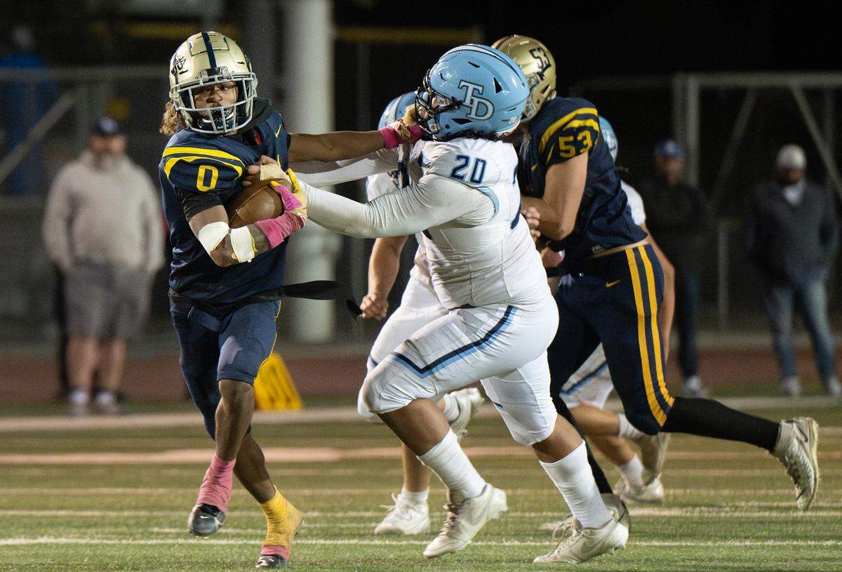 Turlock’s Jeremiah Stine fights off Downey defender Izzy Lopez during the Central California Athletic League game at Turlock High School in Turlock, Friday, Oct. 18, 2024.