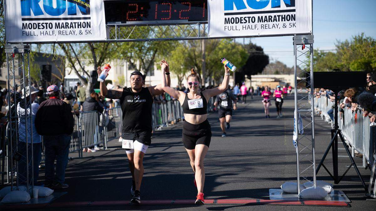 Jose Gonzalez and Gianna Lagorio cross the the finish line, completing the half marathon, in the Modesto Marathon on Sunday, March, 23, 2025. 