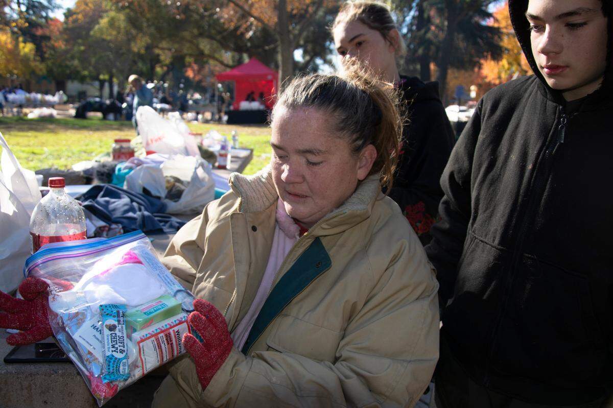 Modesto resident Rebekah Harnden, with her children Devin Marie and John Charles, shows off a care package made for her by a group handing out food and supplies to homeless in Graceada Park Thanksgiving Day 2020 in Modesto, Calif.