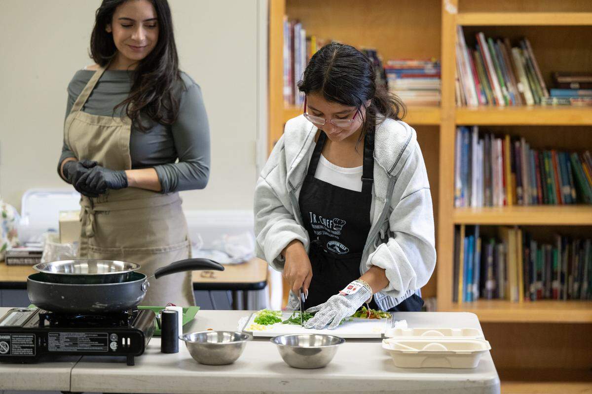 Meriam Jacobs, education programs manager at East Stanislaus Resource Conservation District, left, observes Amaris Hernandez prepare spinach during the Junior Chef after school program at Sipherd Elementary School in Modesto, Calif., Thursday, Sept. 19, 2024.