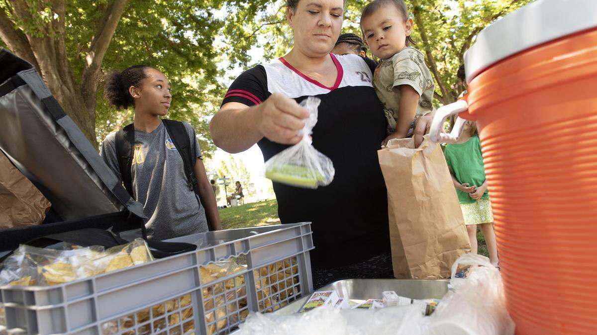 Erin Aguilar selects some lunch item with her son Ben, 2, during the Modesto City Schools summer lunch program in Modesto, Calif., Wednesday, June 19, 2019.
