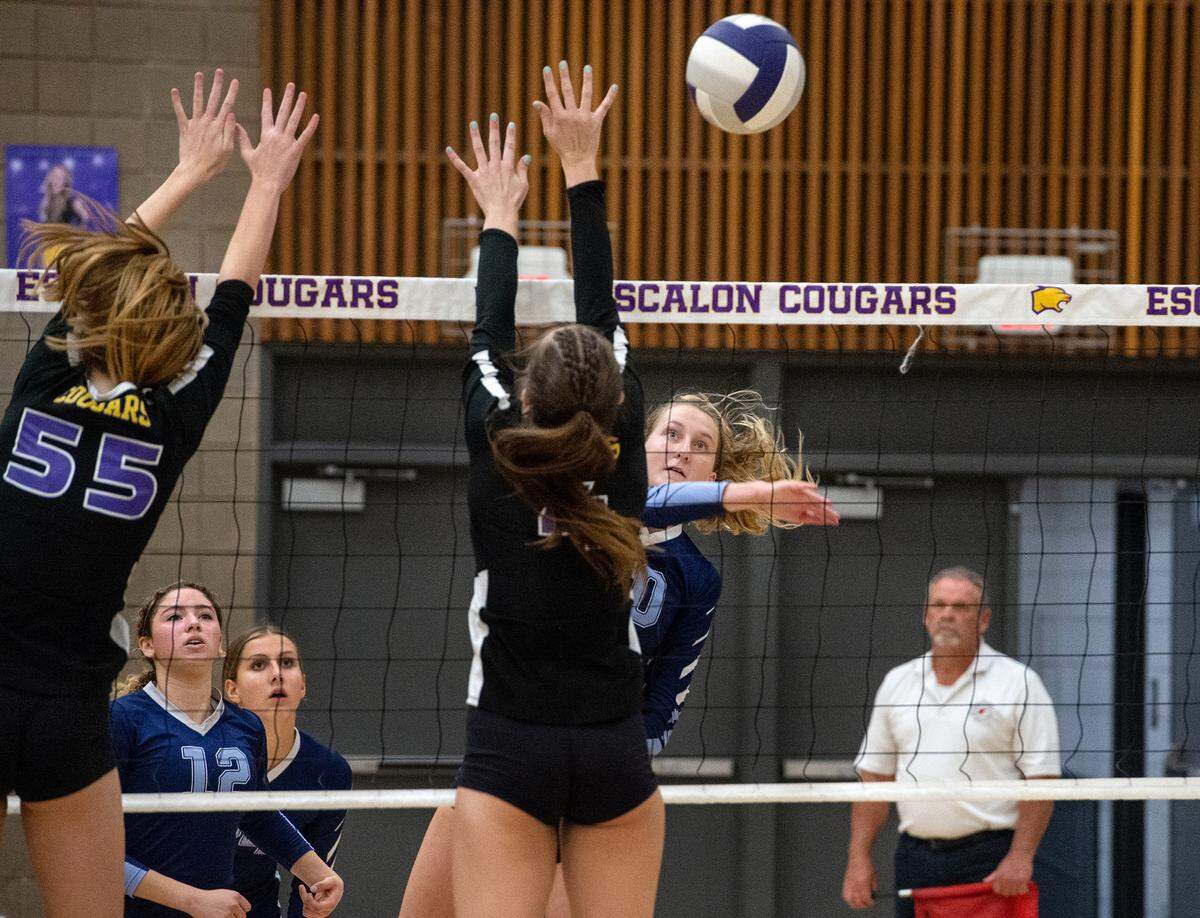 Downey’s Kylie Griffin spikes the ball past Escalon defenders during a non-league match in Escalon, Calif., on Tuesday, September 27, 2022.