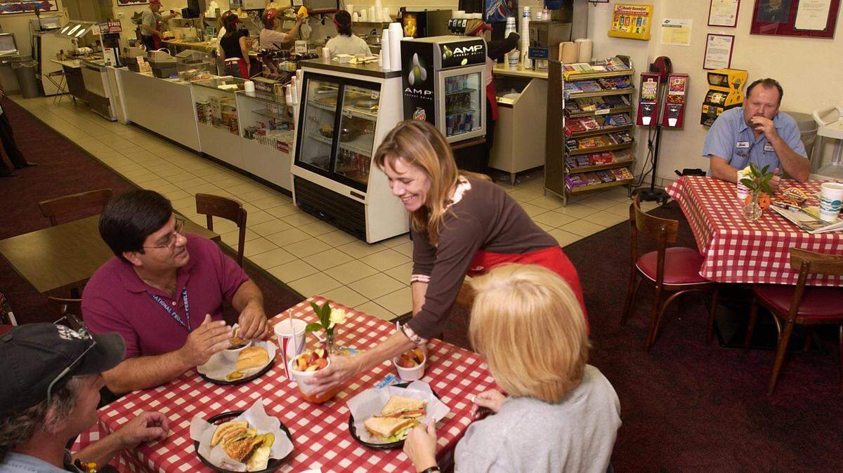 Piccadilly Deli and Sandwich Shop owner Suzie Wirth serves fruit salad to customers (left to right) Bruce Roehr, Jeff Csolak, and Aurora Jacobsen during lunchtime in 2005.