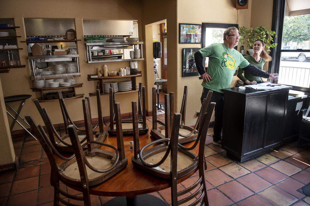 Harvest Moon restaurant owner Mark Smallwood and server Lindsey Gildea, right, handle a small selection of takeout orders at in Modesto, Calif., on Tuesday, March 17, 2020.