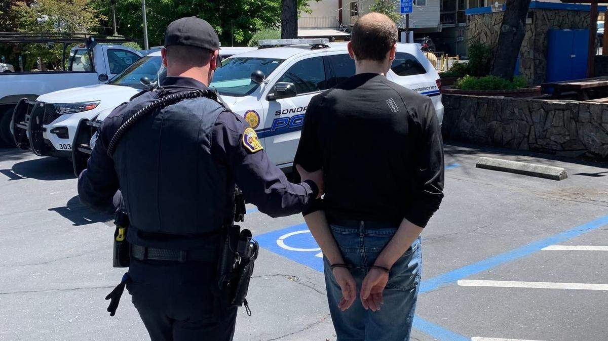Sonora police officers escort a man in handcuffs following the execution of a search warrant at a residence in Sonora on April 29, 2026. Authorities said the investigation stemmed from a cyber tip related to child exploitation.