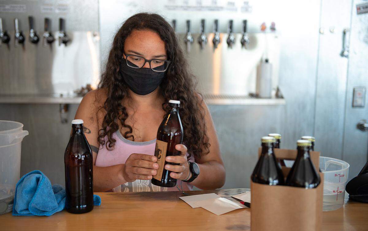 Owner Abena Darden labels custom bottled beer at contentment Brewing Co. in Modesto, Calif., on Saturday, March 6, 2021.