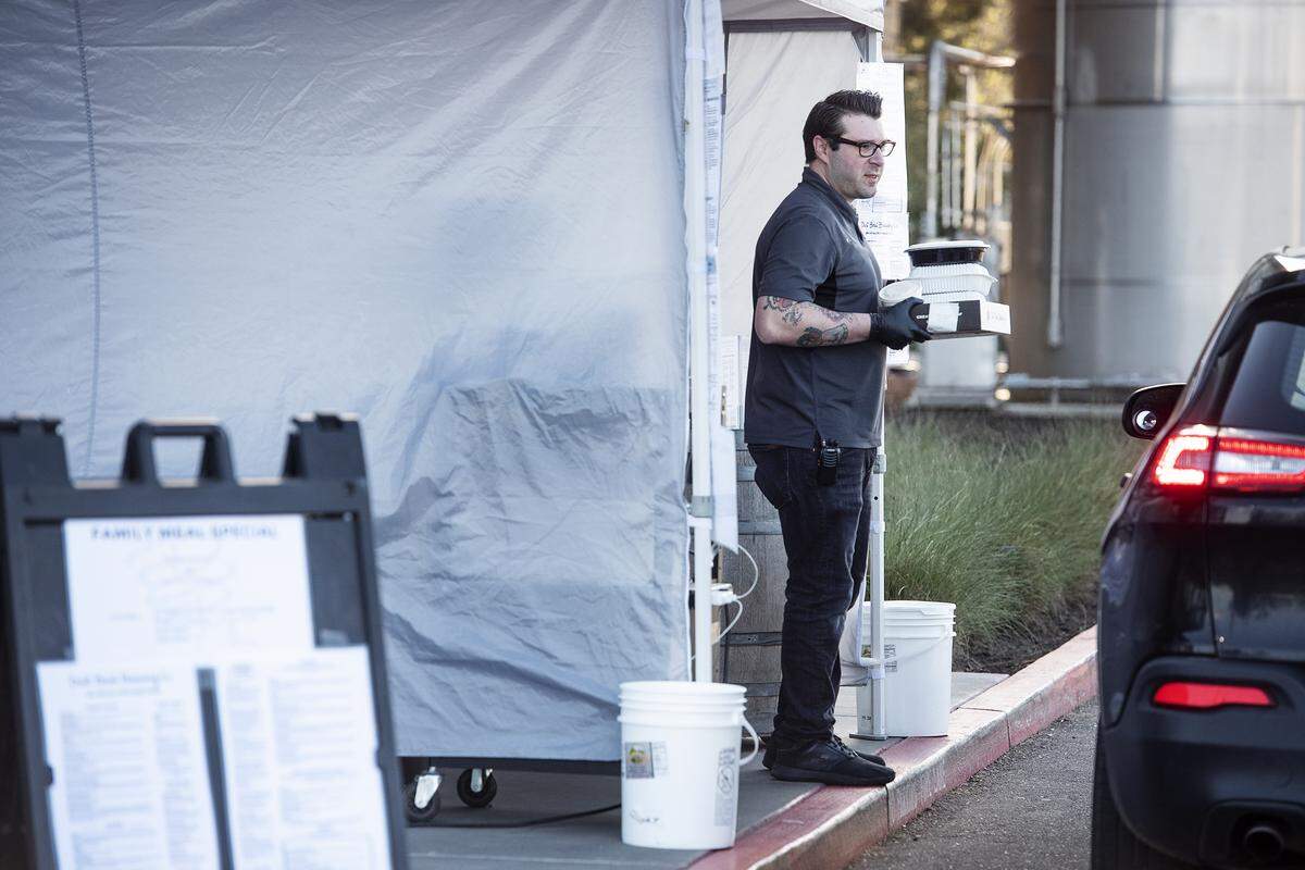 Dust Bowl Brewing manager Spencer Jones delivers take-out food and packaged beer to customers waiting in their cars at their brewery in Turlock, Calif., on Friday, March 20, 2020.