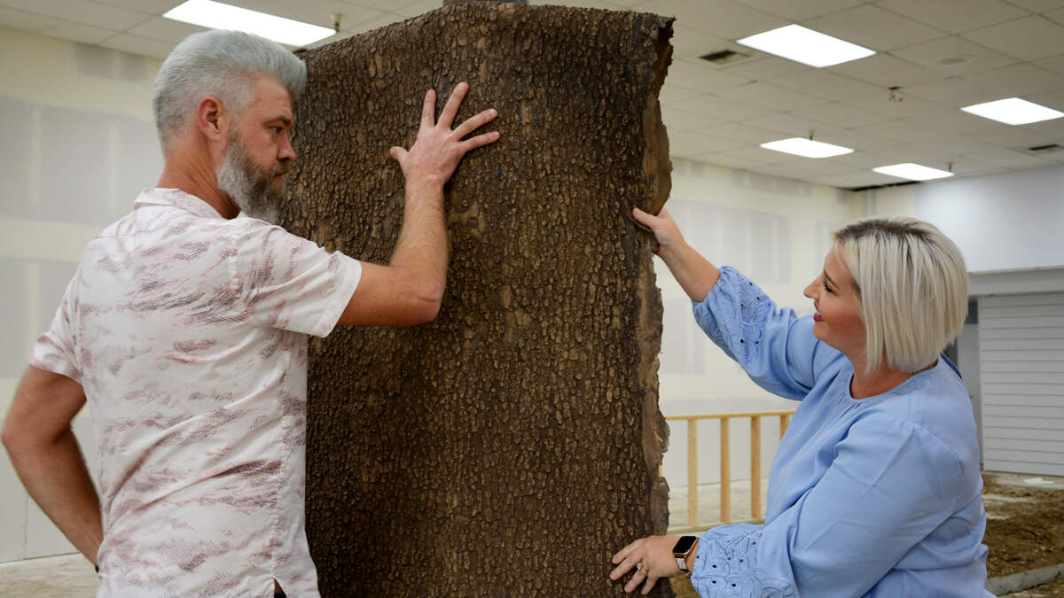 Mike Day (left) holds up faux tree bark for Elora Jorgenson to inspect in a new indoor dog park they are building in Modesto, Calif. March 3, 2022