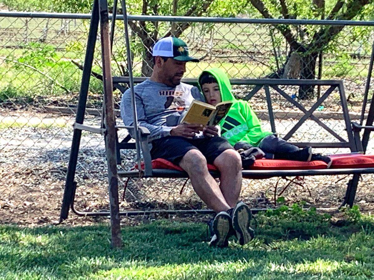 Charly Garza, a Hickman Charter School fourth-grade teacher, reads with his second-grade son, Calvin, who is home-schooled through the Hickman district.