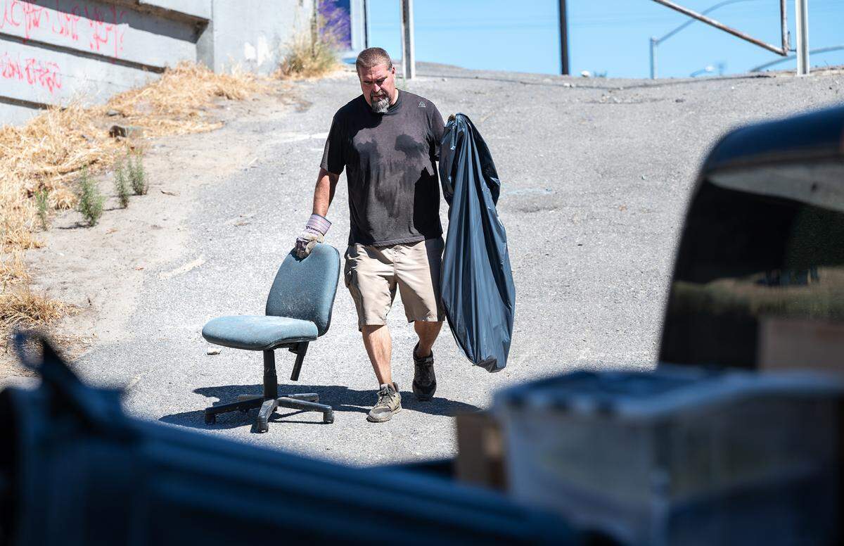 Operation 9-2-99 organizer Chris Guptill rounds up some garbage during the monthly clean-up at Gateway Park in Modesto, Calif., on Saturday, July 16, 2022.