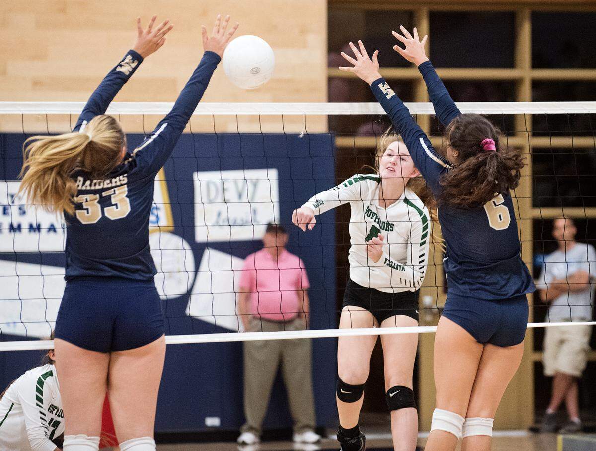 Manteca’s Karlie Spohn spikes the ball past Central Catholic defenders Grace Mathias (33) and Hannah Castillon (6) during the Valley Oak League match at Central Catholic High School in Modesto, Calif., on Thursday, Oct. 4, 2018.