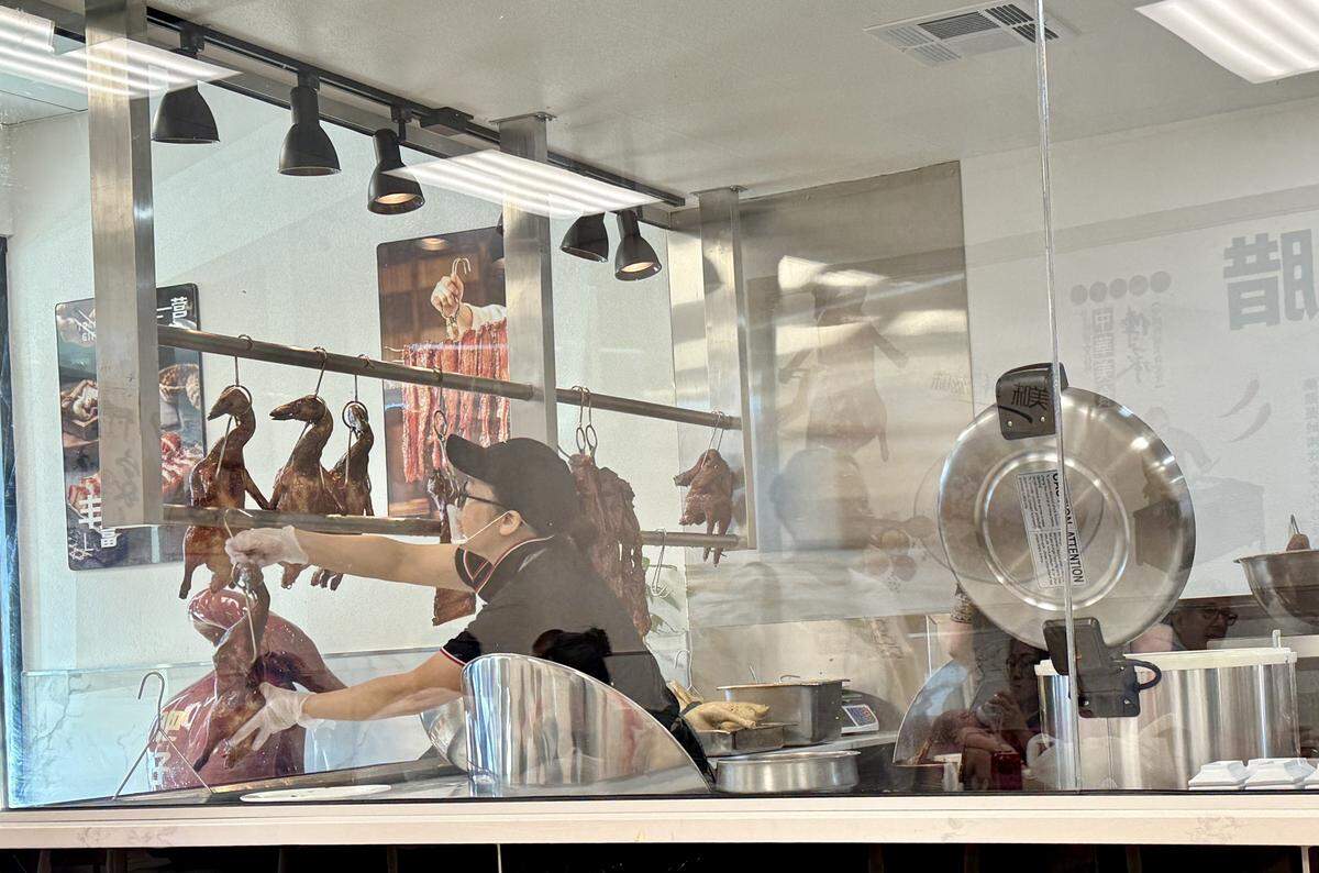 An employee hangs freshly roasted ducks on meat hooks at Fat Boy Roasted Delights in Modesto, Calif., on Monday, Nov. 3, 2025.