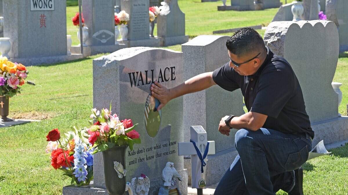 Oscar Ramos, family of fallen officer Dennis Wallace,visits his gravesite Wednesday morning May 2, 2018 at conclusion of the Peace Officers Memorial ceremony at Lakewood Memorial Park in Hughson, Calif.