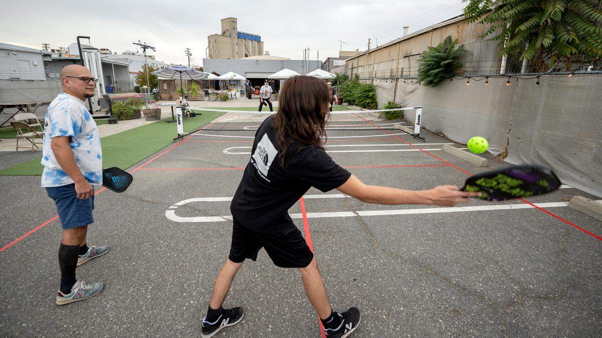 Contentment Brewery owner Alejandro Serrato, left, teams up with Lyric Ogilvie for a game of doubles on the brewery’s new pickleball court in Modesto Wednesday, Oct. 22, 2025.  